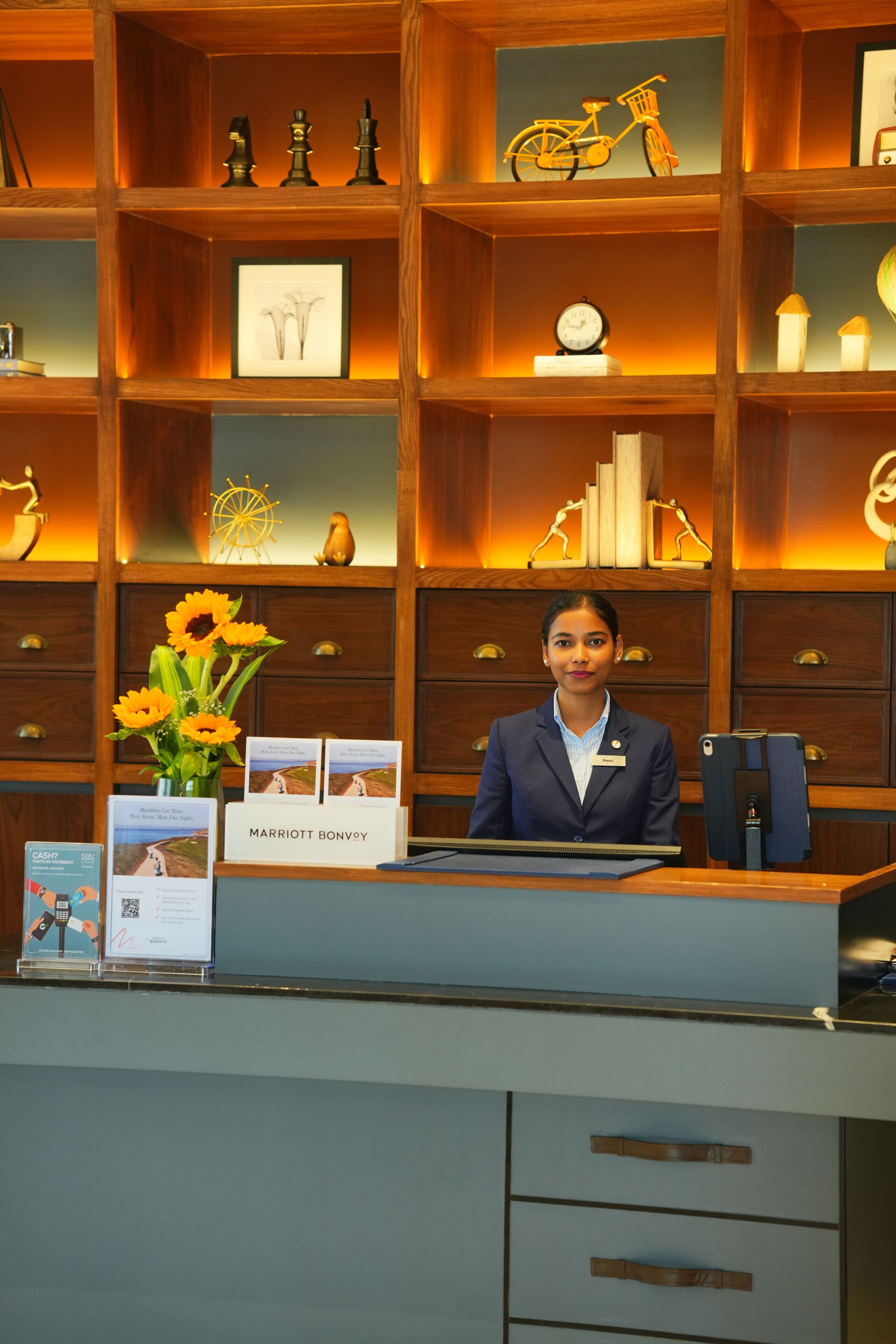 A reception desk with a name tag, a framed picture, a clock, and a vase with flowers.