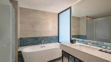A modern bathroom with a freestanding bathtub, a large mirror, and a tiled backsplash.