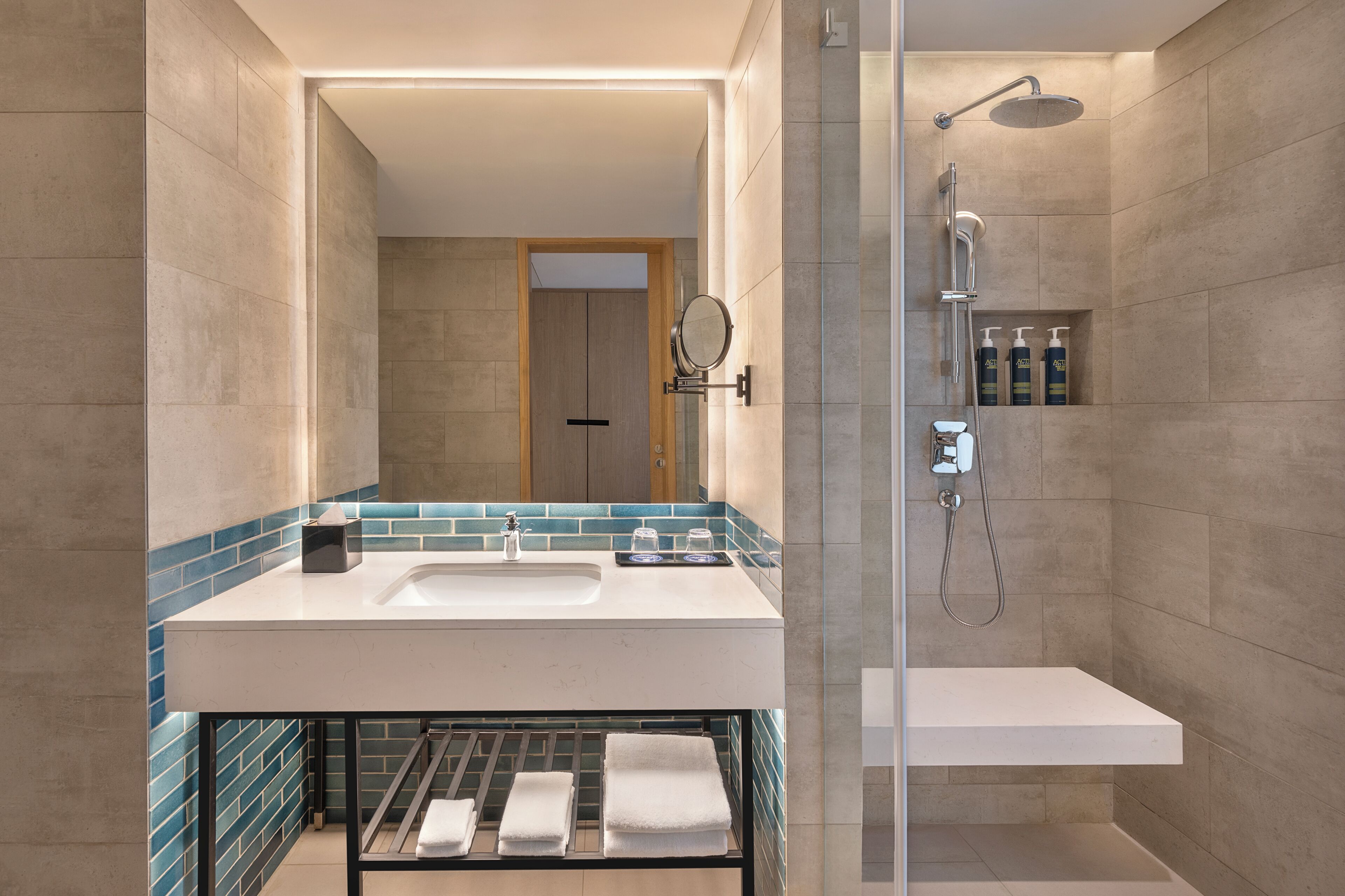 A modern bathroom with a shower, a sink, and a glass-enclosed toilet.
