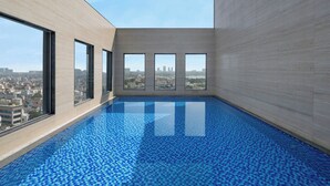 Una piscina interior moderna con vistas a la ciudad, amplios ventanales y suelo de baldosas.