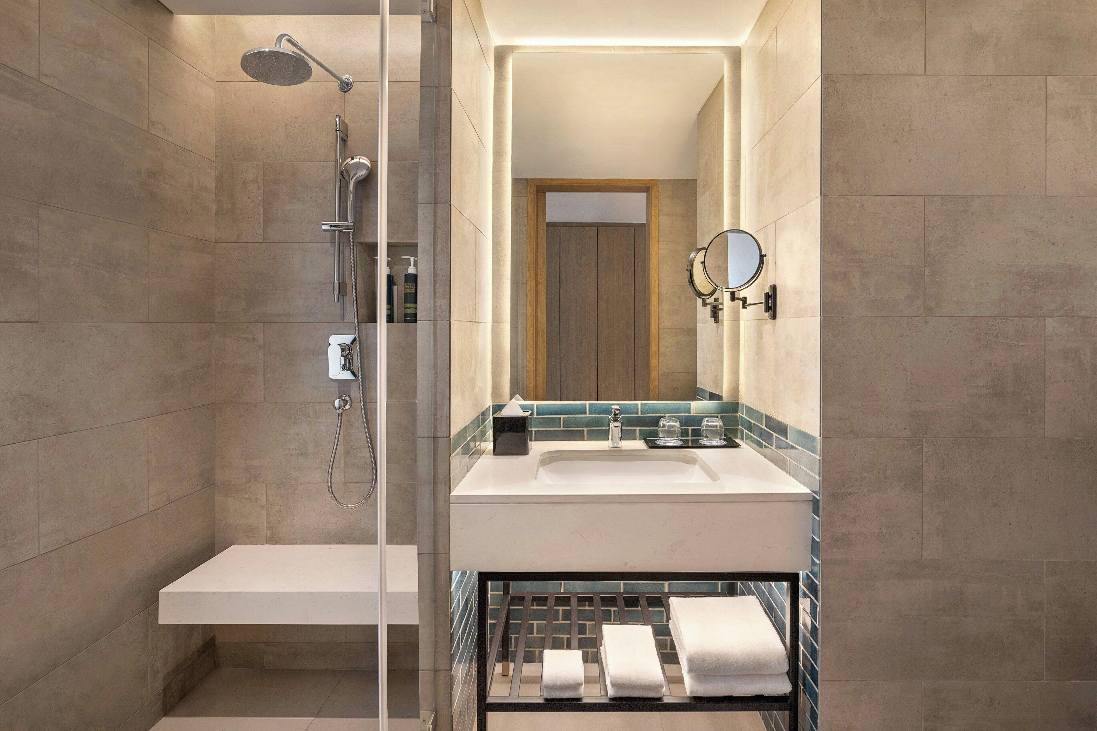 A modern bathroom with a glass-enclosed shower, a white sink, and a mirror with two lights.