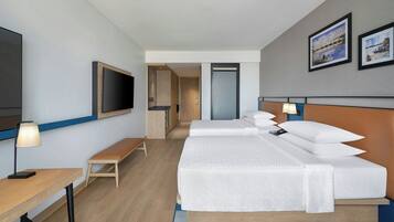 A hotel room with two beds, a TV, a desk, and a bench.