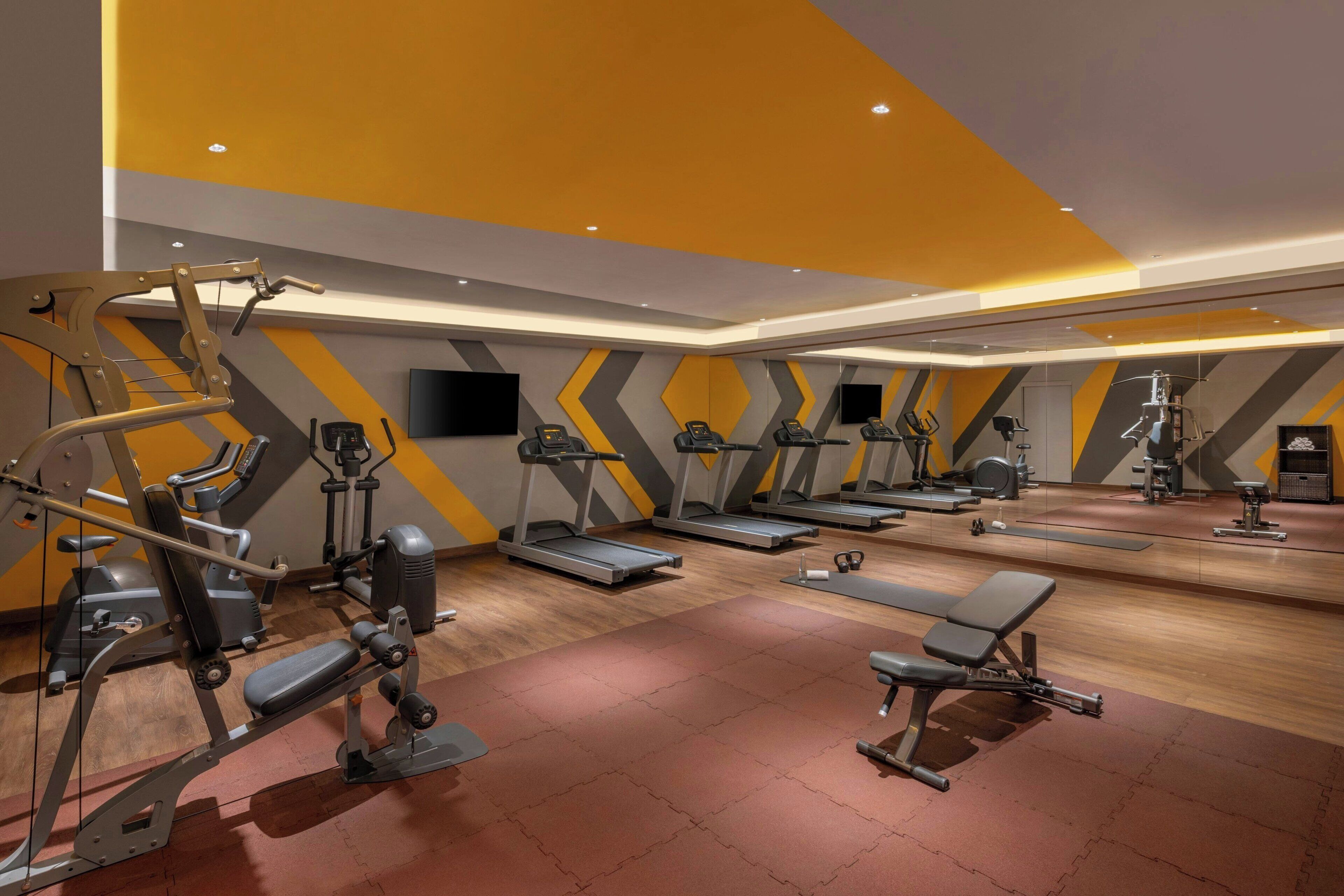 A gym with treadmills, weight machines, and benches.