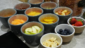 A variety of fruit bowls containing sliced apples, bananas, strawberries, and blueberries.