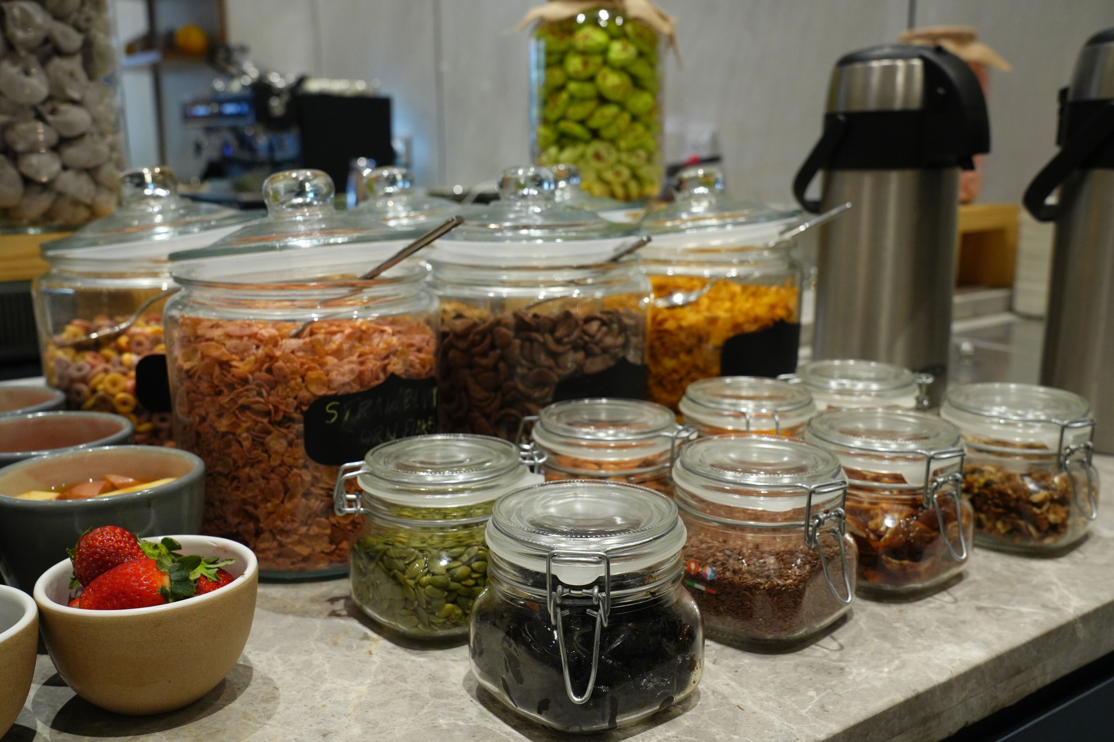A buffet with various food items in glass containers, including a bowl of strawberries.