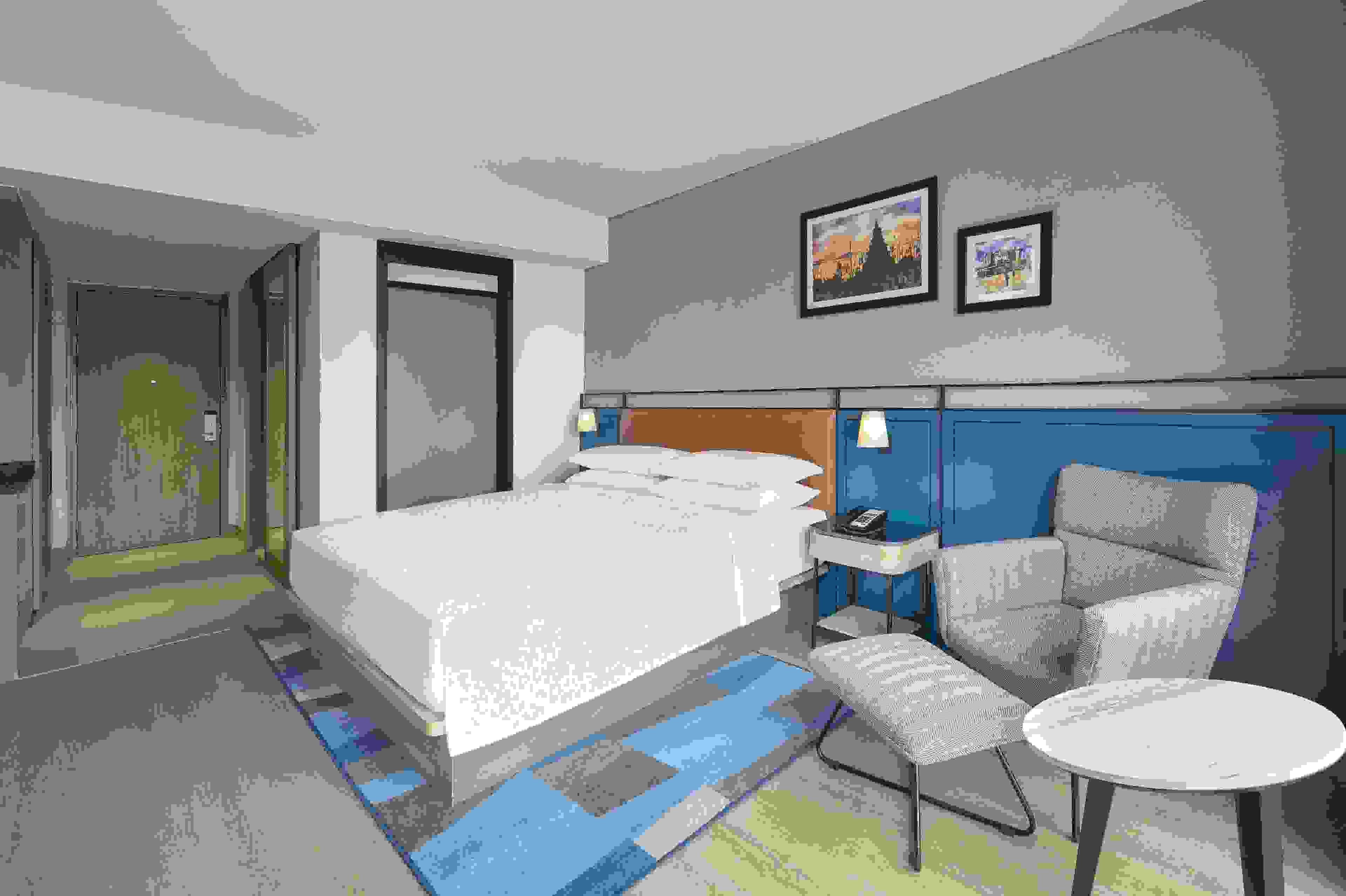 Une chambre d’hôtel avec un lit, une chaise, une petite table et une table de chevet.