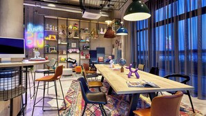 Une salle de réunion moderne, dotée d’une grande table, de chaises et d’une bibliothèque remplie de divers objets.