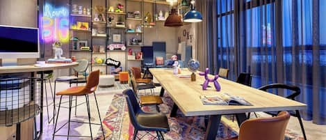 Una sala de reuniones moderna con una gran mesa, sillas y una estantería llena de objetos diversos.