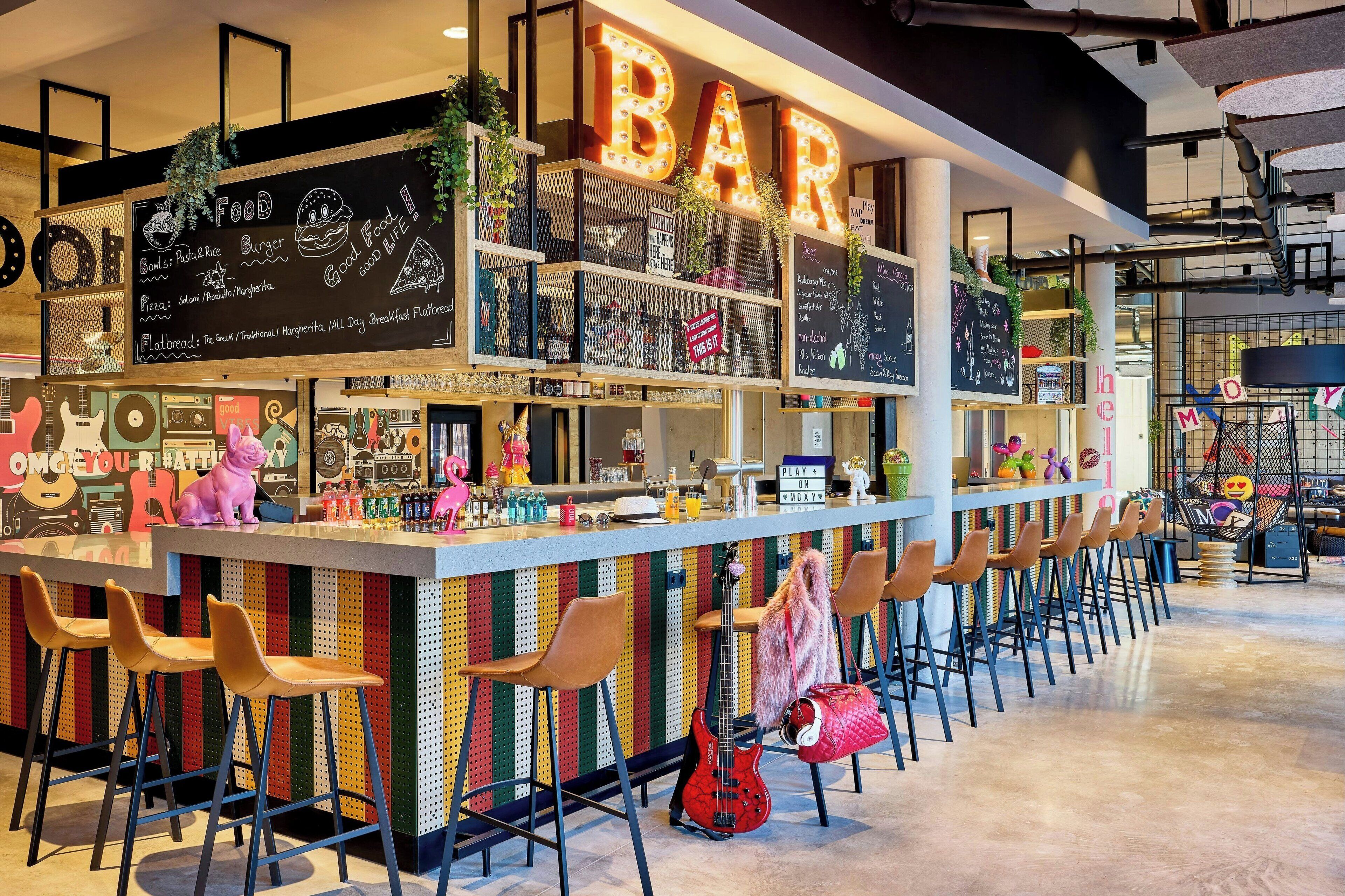 A bar area with a long counter, multiple stools, and a chalkboard menu.