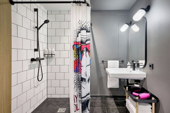 Un baño moderno con ducha, un lavabo blanco y un espejo.