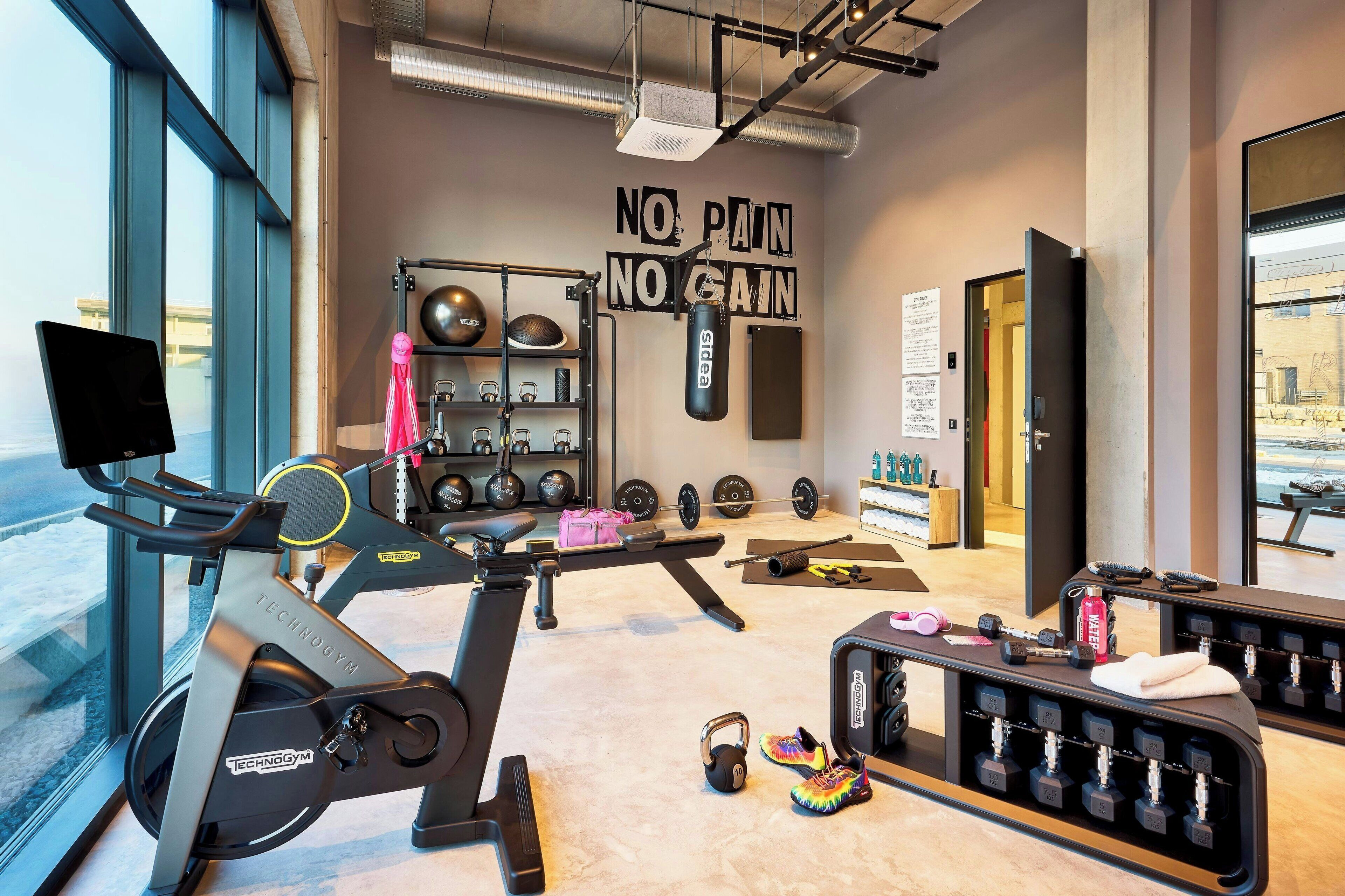 A gym with exercise equipment, a punching bag, and motivational wall text.