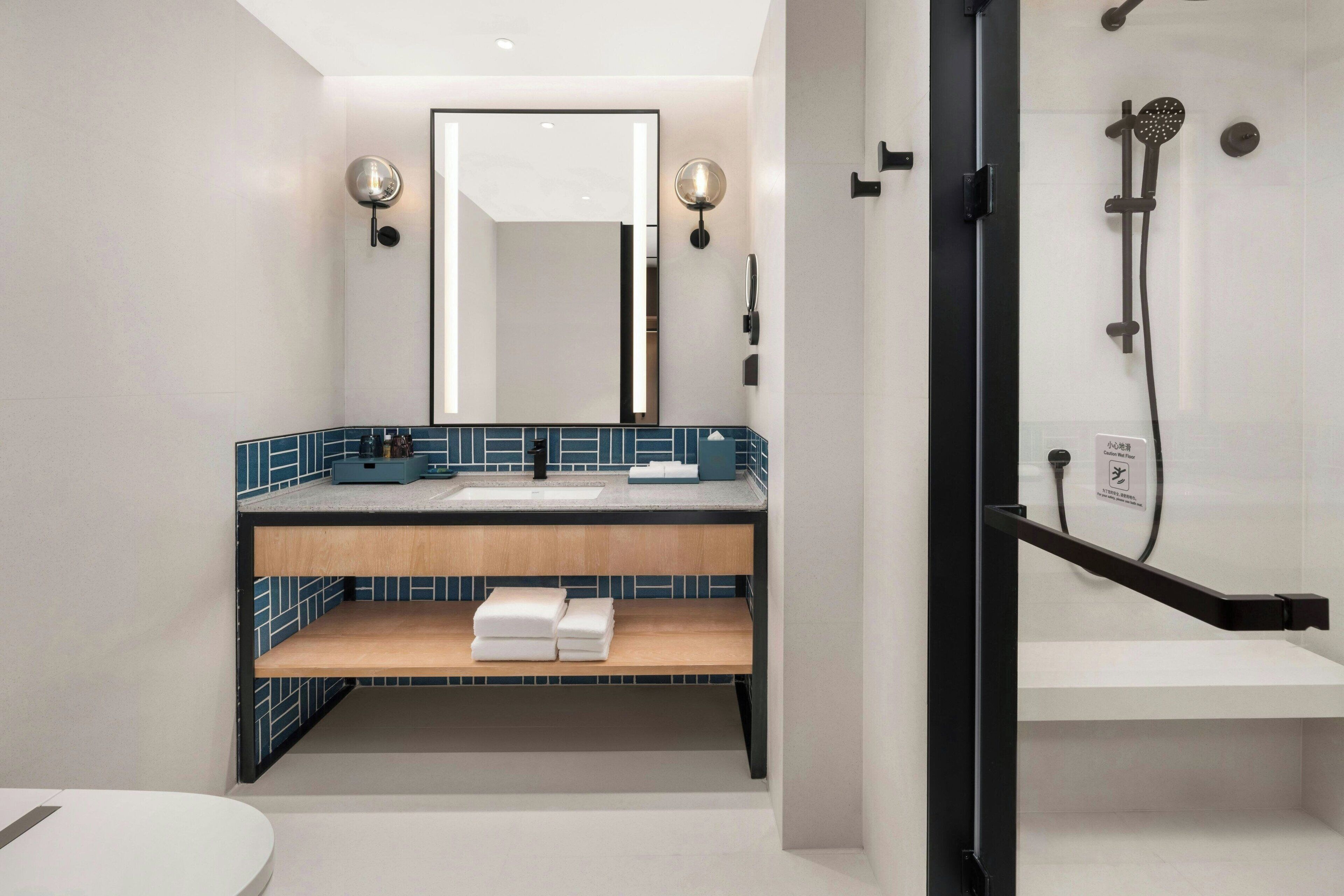 A modern bathroom with a sink, mirror, and shower.