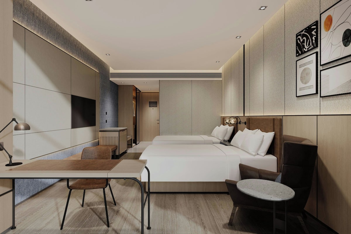 Une chambre d’hôtel moderne, dotée d’un grand lit, d’un bureau avec une chaise, d’une petite table ronde et d’un canapé.