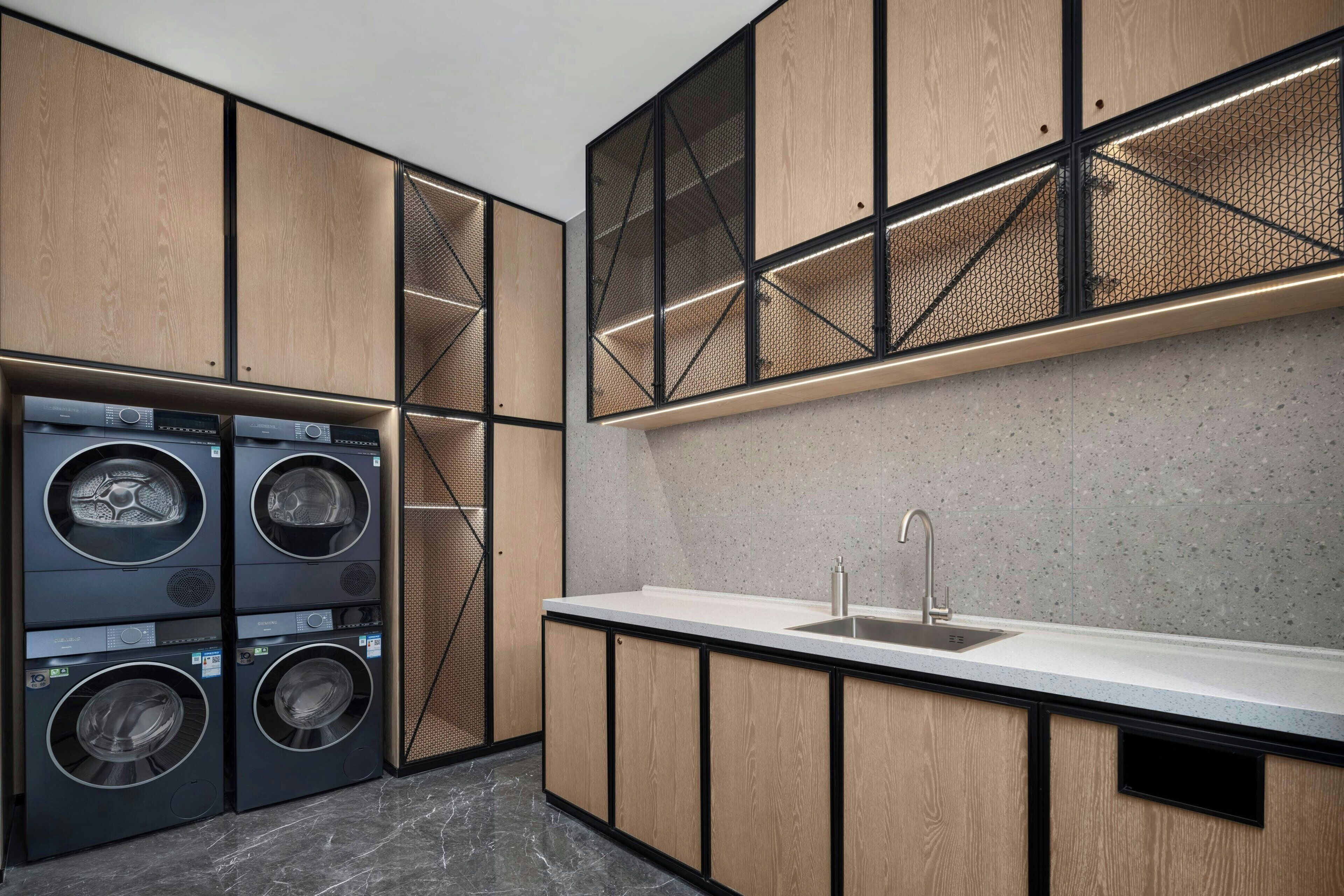 Une cuisine moderne dotée d’appareils électroménagers intégrés, d’un évier encastré dans le plan de travail et de meubles de rangement en bois.