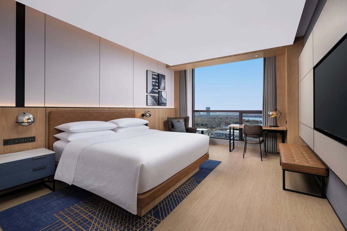 Une chambre d’hôtel moderne avec un grand lit, un bureau, une chaise et un téléviseur.