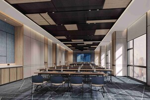 A conference room with a long table, chairs, and a large screen at the front.