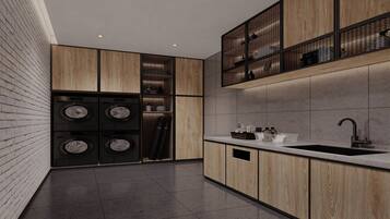 A modern kitchen with wooden cabinetry, a built-in washing machine, and a stainless steel sink.