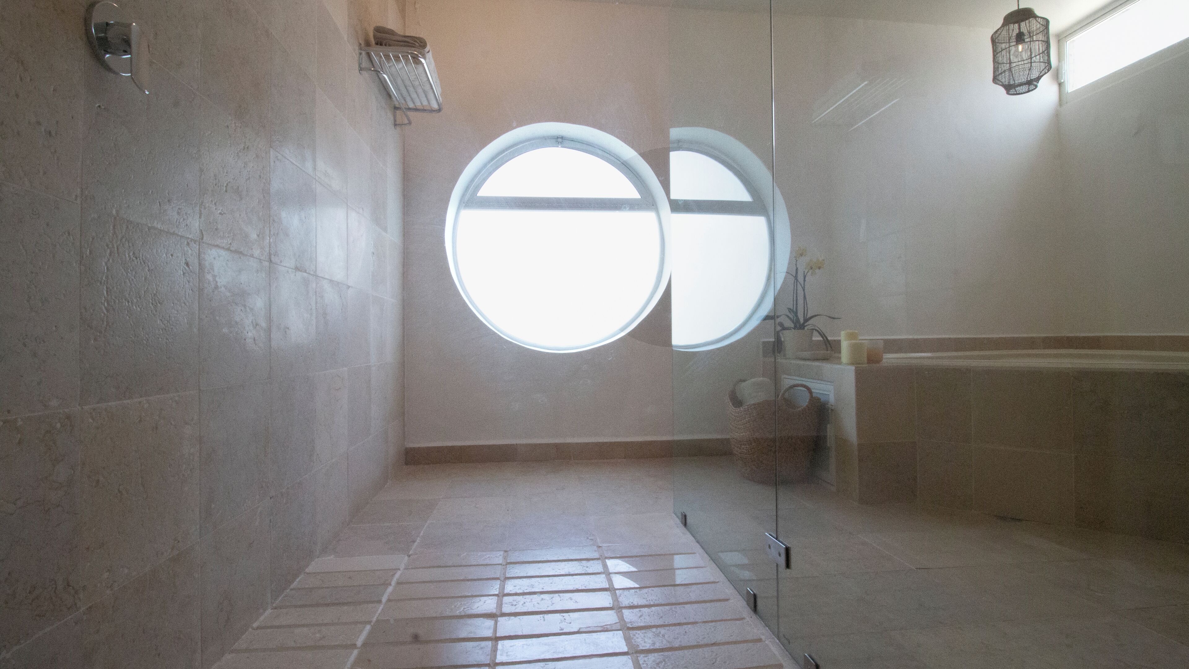 Un baño con un ventanal circular grande, ducha y bañera.