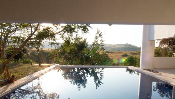 A swimming pool with a clear view of the surrounding landscape, including trees and distant hills.