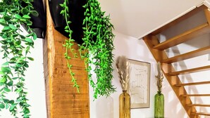 A room with a wooden beam, white cabinets, and hanging green plants. - "La Citadelle - Duplex with view of Château-fort (Sedan)