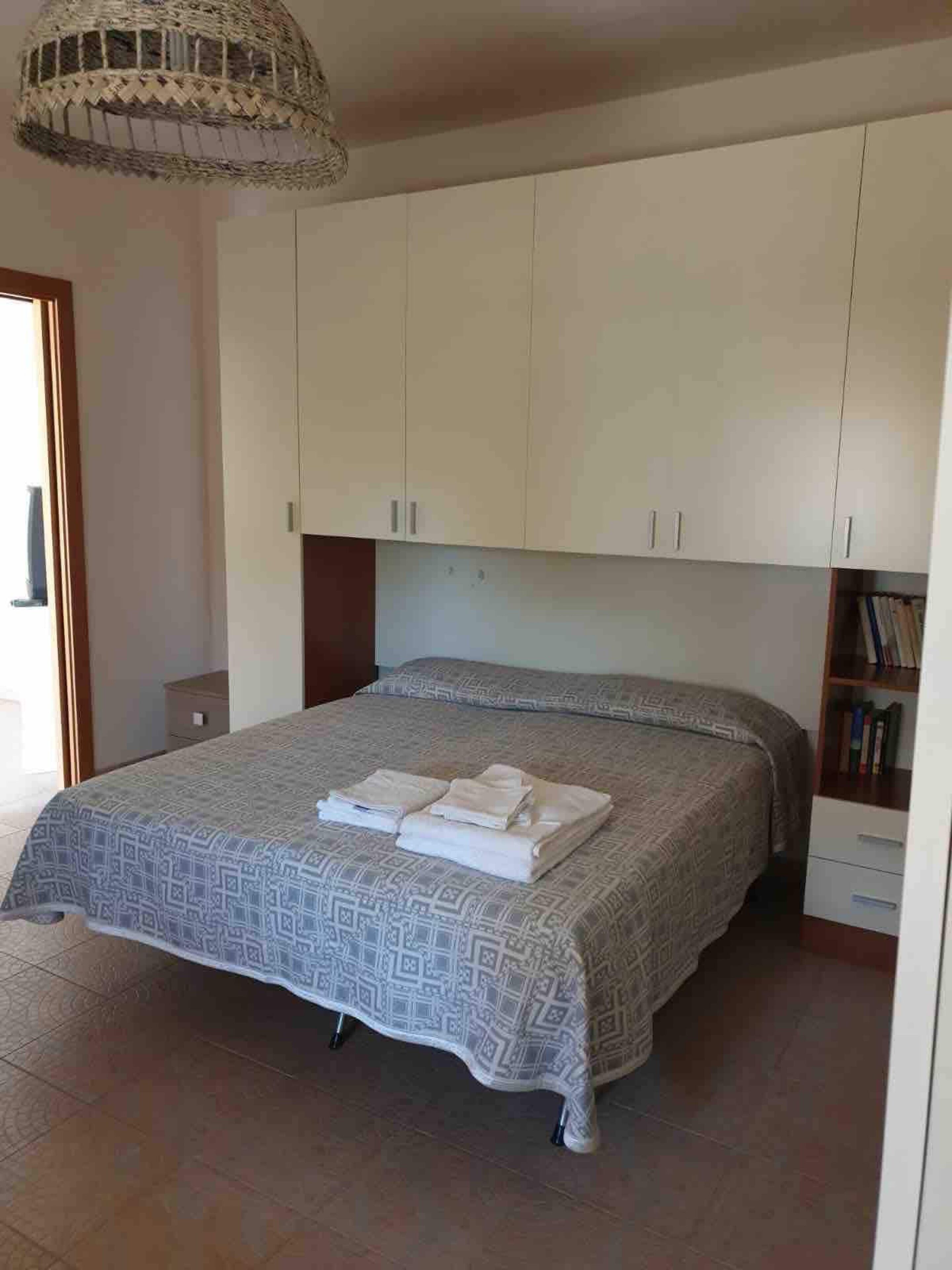 Une chambre à coucher avec un lit, une armoire et un luminaire suspendu.
