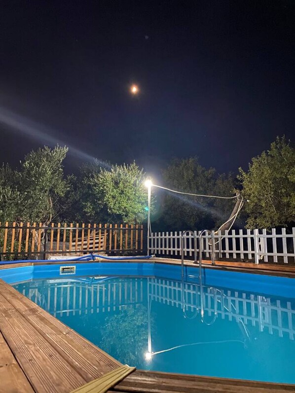 A swimming pool with a wooden deck and a white fence.