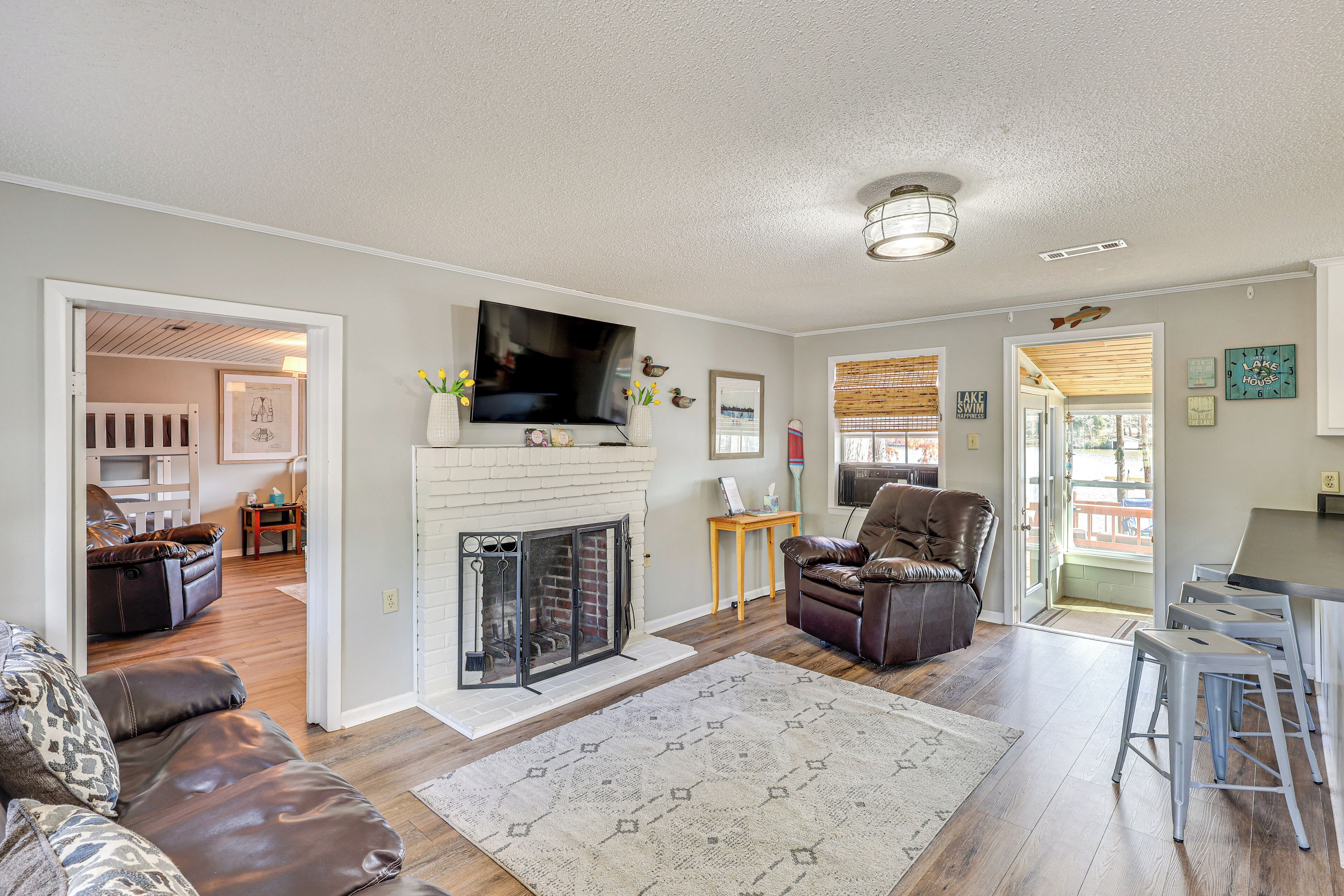 A spacious living room with a fireplace, a television, and a dining area with bar stools.
