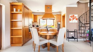 Une cuisine moderne avec des meubles en bois, un îlot central doté de chaises et un escalier en métal noir.
