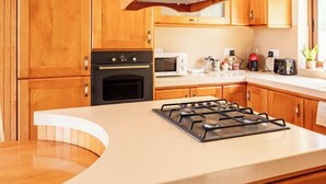 Une cuisine moderne avec des meubles en bois, un îlot central, une cuisinière et un four à micro-ondes.