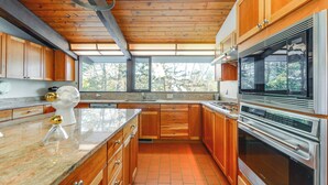 Eine moderne Küche mit Holzausstattung, einer Granitarbeitsplatte und Edelstahlgeräten.