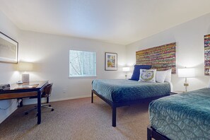 Une chambre d’hôtel avec deux lits, un bureau et une fenêtre équipée de stores.
