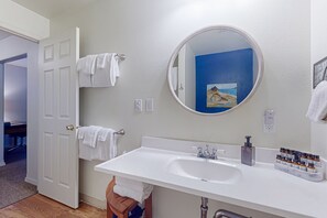 Une salle de bain avec un lavabo blanc, un miroir rond et un porte-serviettes.