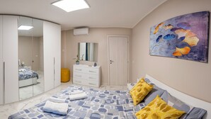A bedroom with a bed, a wardrobe, a mirror, and a painting on the wall. - Elegant tourist accommodation facing metro C (Roma)