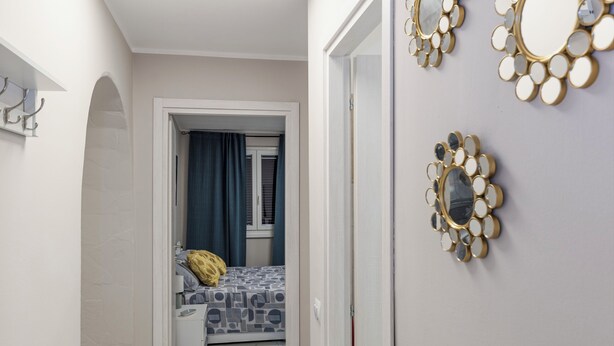 A hallway with a bed in the background, a ceiling light, and decorative mirrors on the wall. - Elegant tourist accommodation facing metro C (Roma)