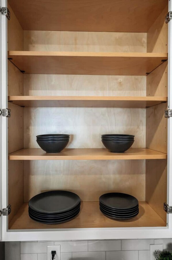 Un mueble de cocina con tres estantes, cada uno con cuencos y platos negros.
