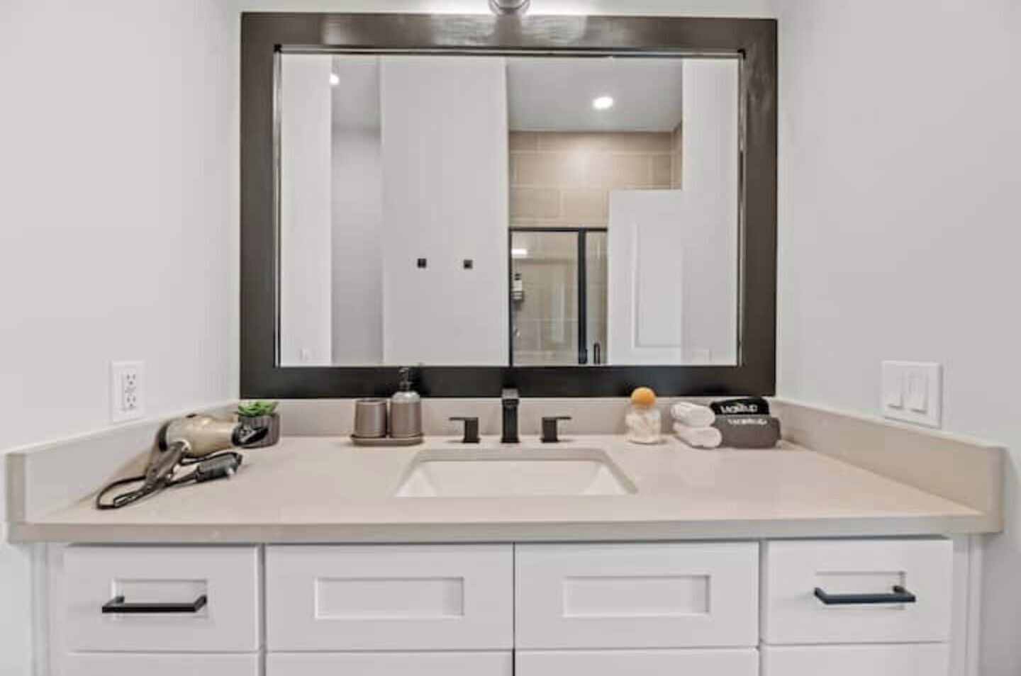 Une salle de bain avec un grand miroir, deux lavabos et un meuble-lavabo doté de tiroirs.