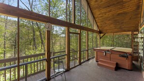 A wooden deck with a bench and a wooden cabinet, overlooking a forested area.