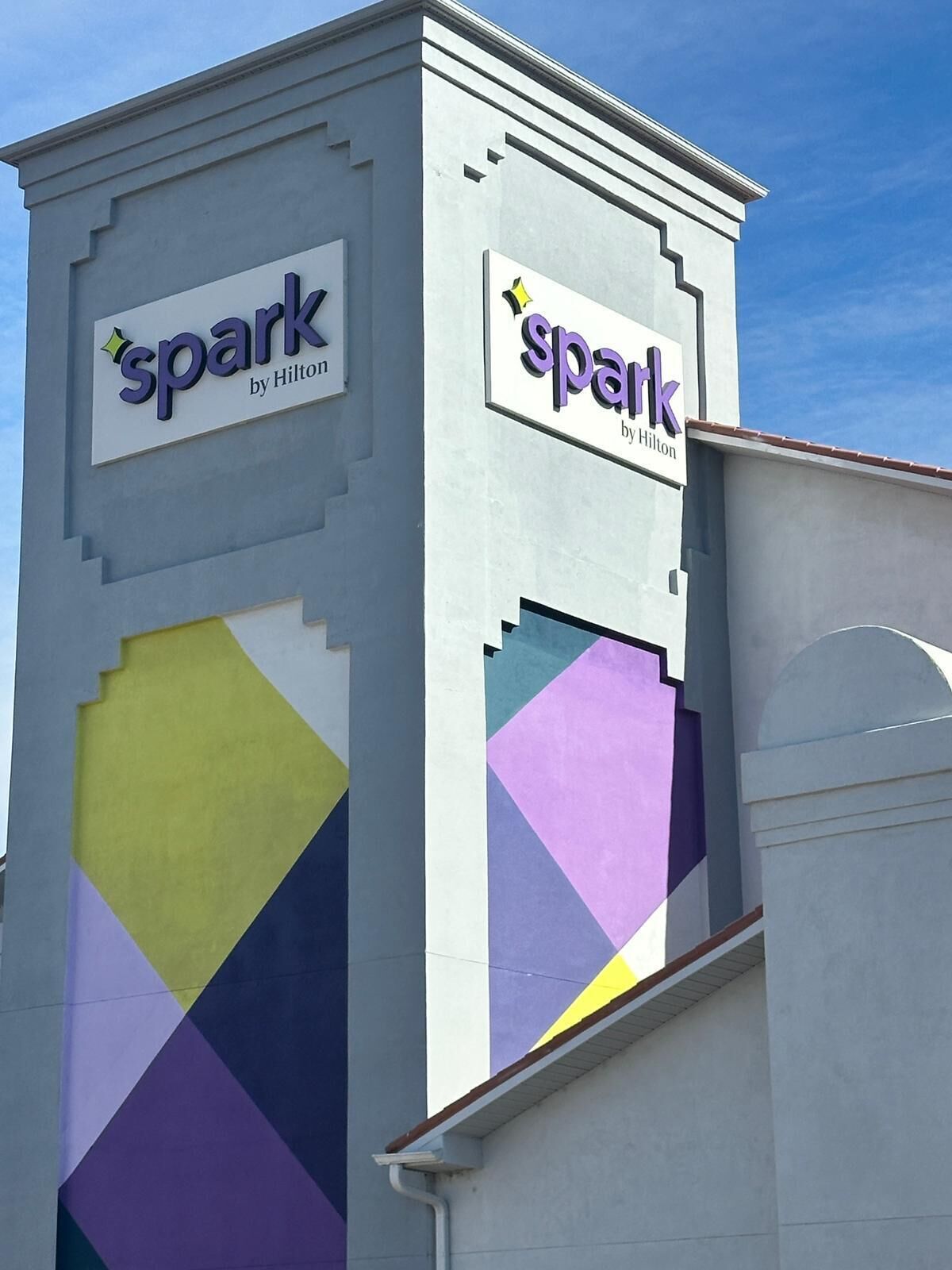 A hotel sign with the name 'spark by Hilton' and a geometric design on the facade.