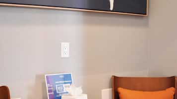Ein Hotelzimmer mit zwei Stühlen, einem kleinen Tisch, einer Taschentuchbox und einem Schild zu Hilton Honors.