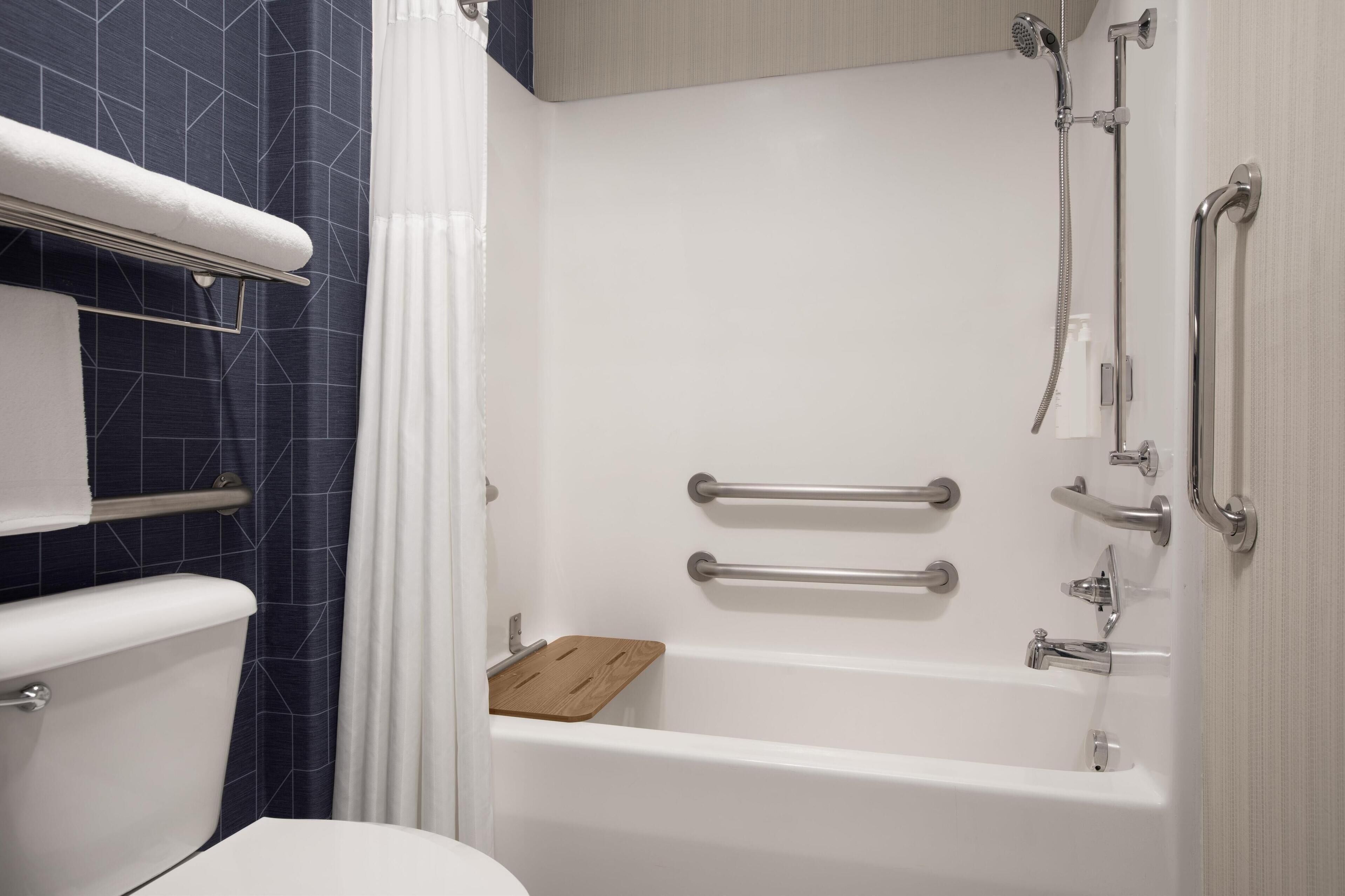 A modern bathroom with a bathtub, shower, and toilet.