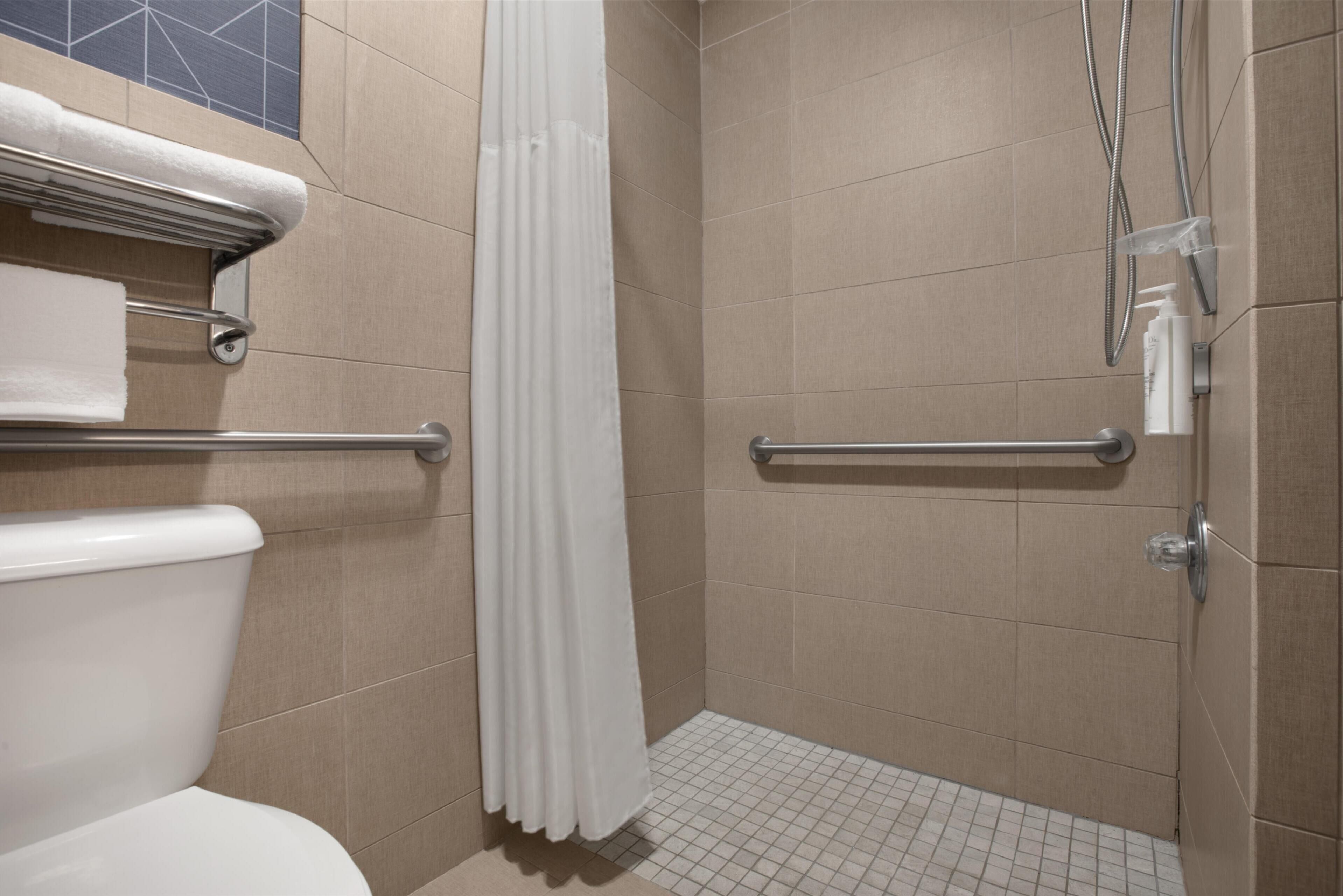 Ein modernes Badezimmer mit Dusche, Haltegriffen und Toilette.