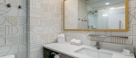 Un baño moderno con un revestimiento mural de diseño geométrico, un espejo grande, un lavabo y un inodoro.