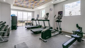 A gym with treadmills, elliptical machines, and free weights.