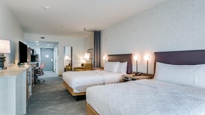 A hotel room with two beds, a desk, and a chair.