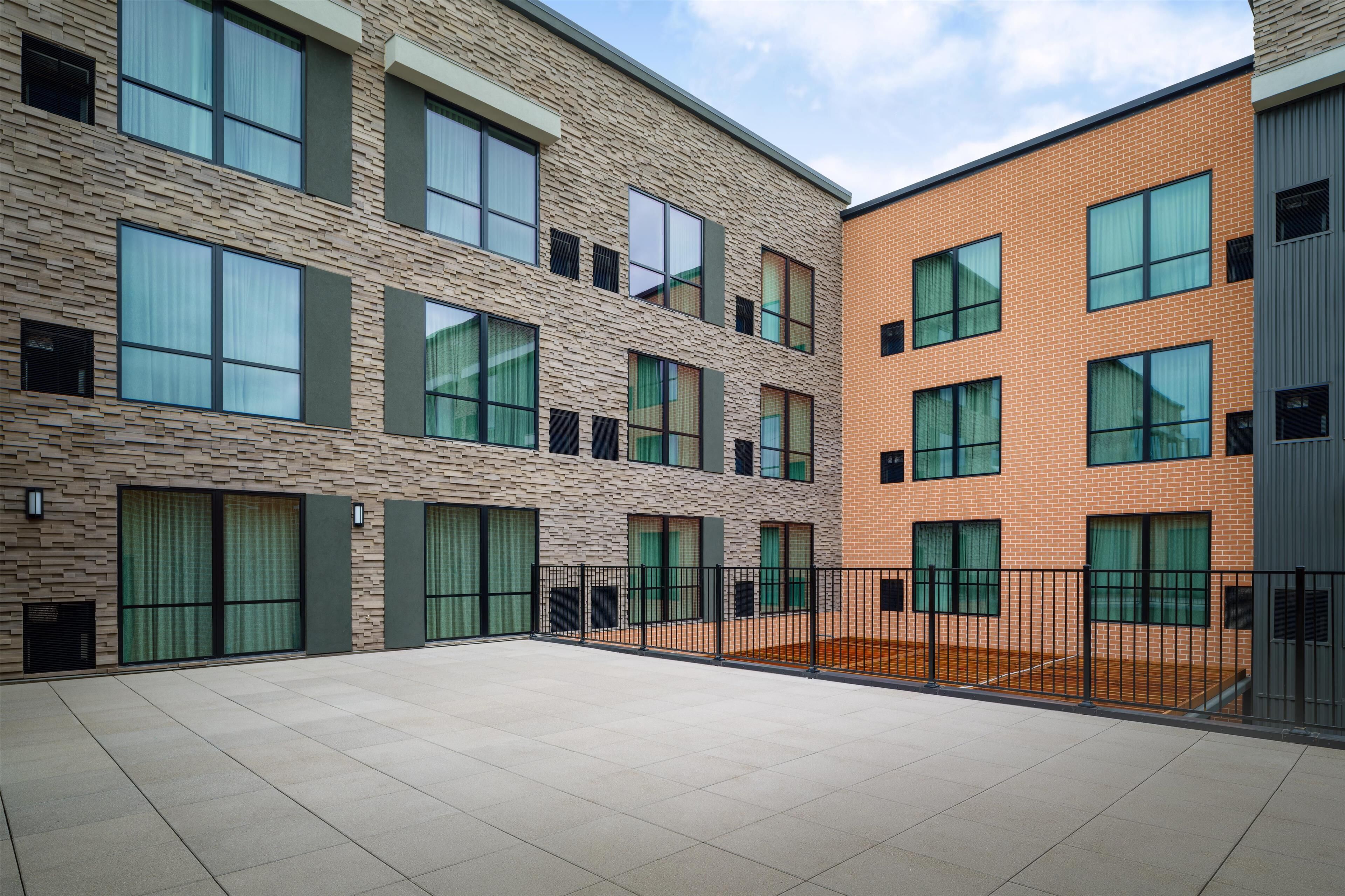 Un immeuble à plusieurs étages doté d’une cour intérieure. L’immeuble présente une façade en briques, de grandes fenêtres et un toit plat.