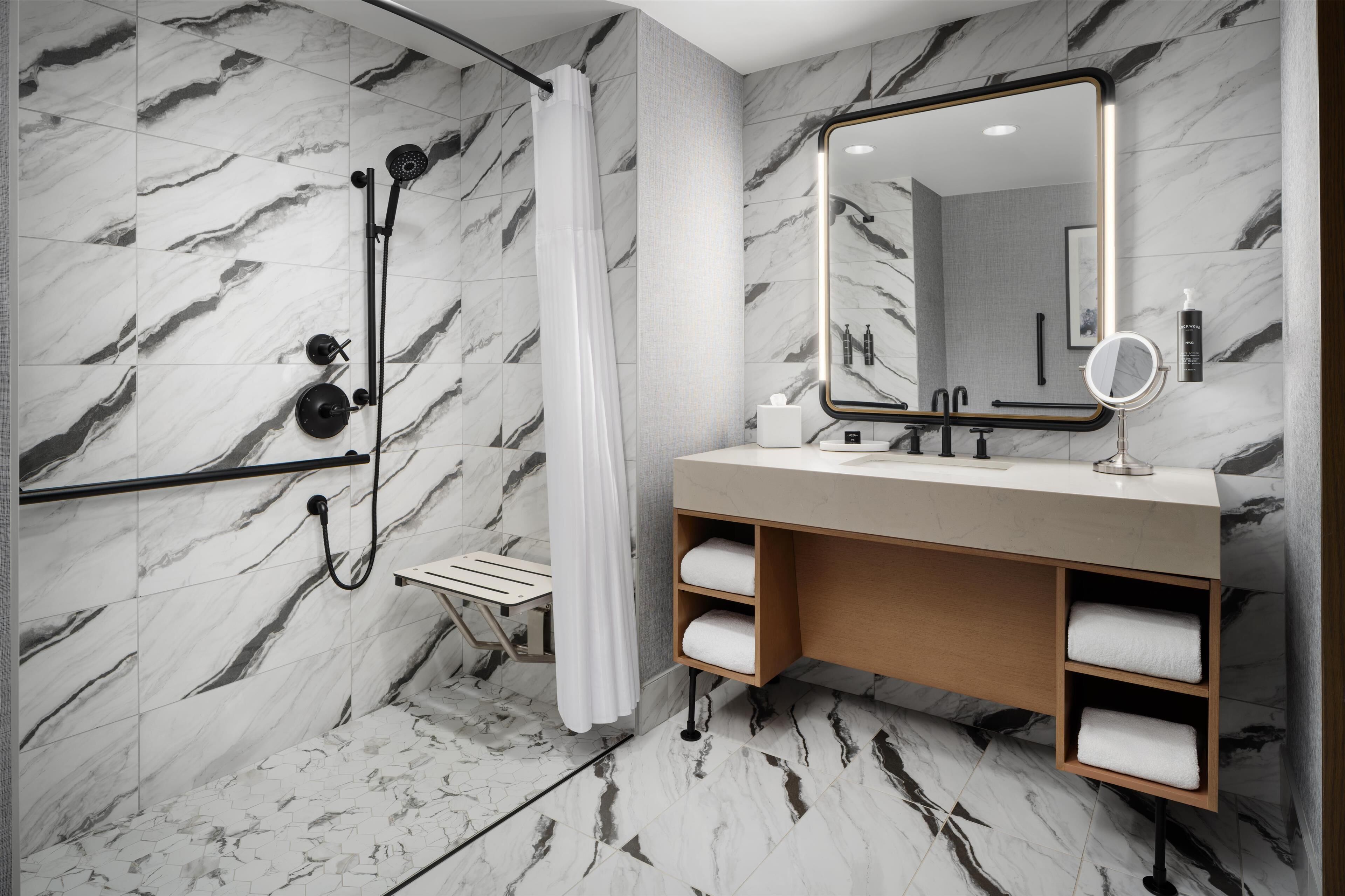 A modern bathroom with a shower, a vanity with a mirror, and marble-patterned walls.