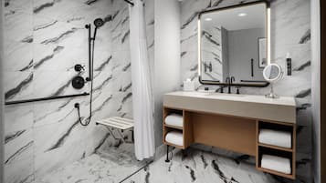 A modern bathroom with a shower, a vanity with a mirror, and marble-patterned walls.