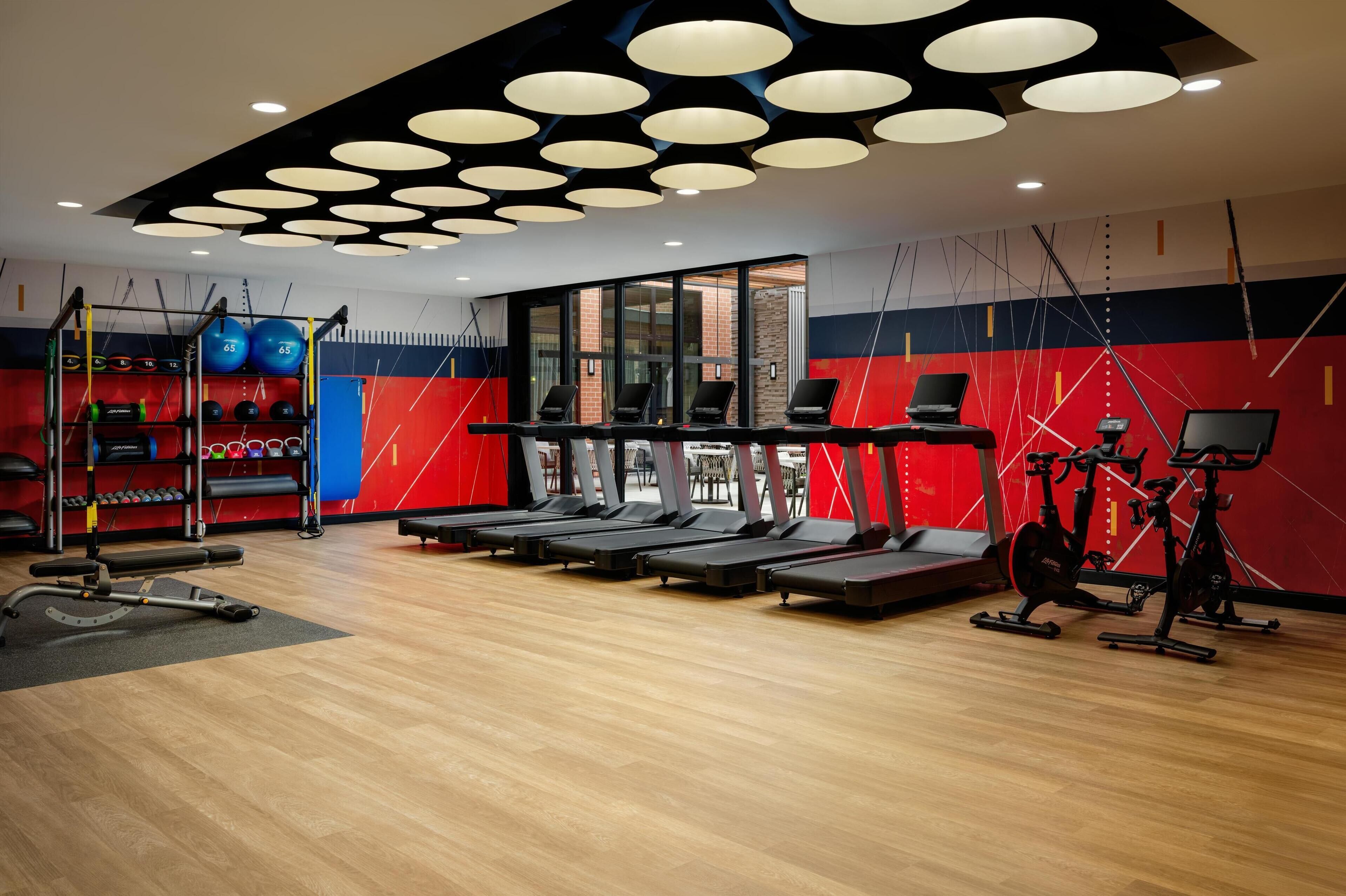 Une salle de sport équipée de tapis de course, de vélos d’appartement et de matériel de musculation.