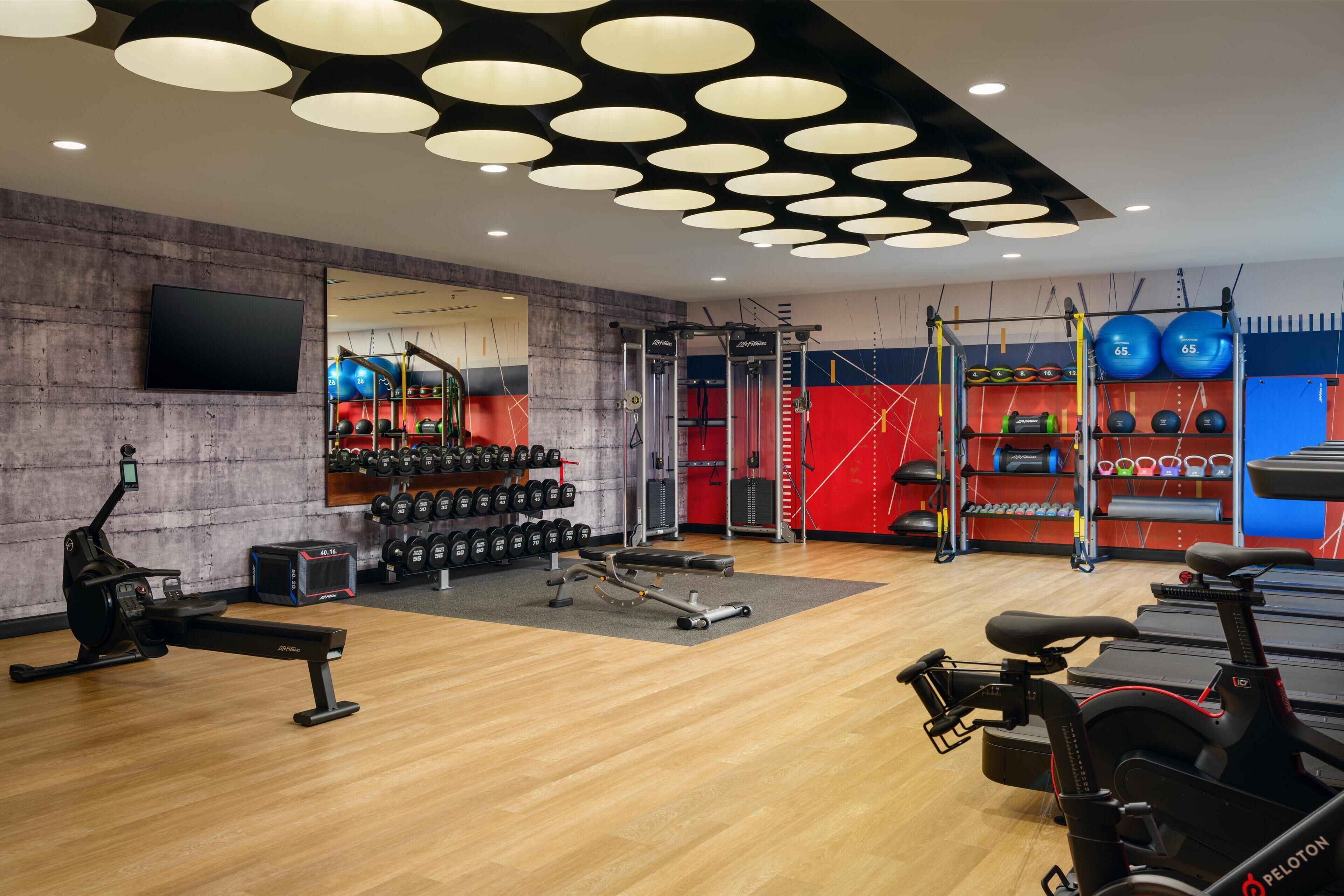 A gym with exercise equipment, weights, and a mirrored wall.
