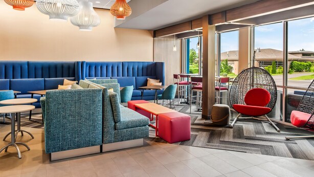 Een moderne lounge met zithoeken, een groot raam met uitzicht op de omgeving en hanglampen.